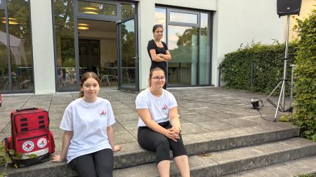 Zwei SchulsanitäterInnen sitzen auf einer Treppe und lächeln in die Kamera