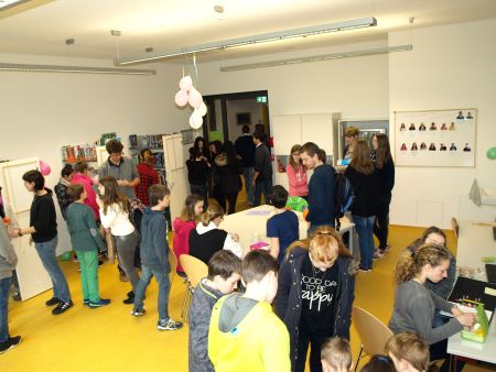 Schüler und Schülerinnen stehen in Grüppchen in der Schulbücherei zusammen