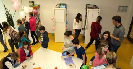 Schüler*innen sitzen an den Tischen der Schulbücherrei