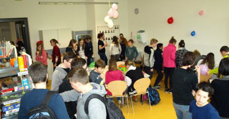 Schüler*innen stehen und sitzen in der schulbücherrei