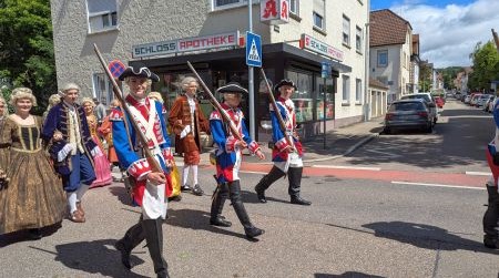 Gruppe verkleideter Personen mit Gewehren in der Hand, über die Schulter gelegt