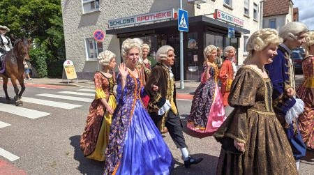 Altmodisch verkleidete Frauen und Herren, eine Frau winkt
