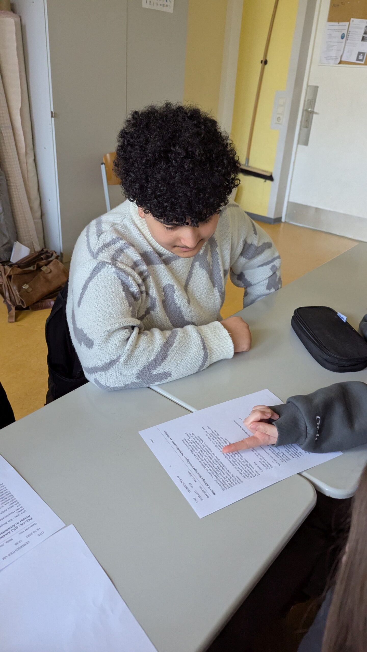 zwei Schüler unterhalten sich am Tisch über ein Arbeitsblatt