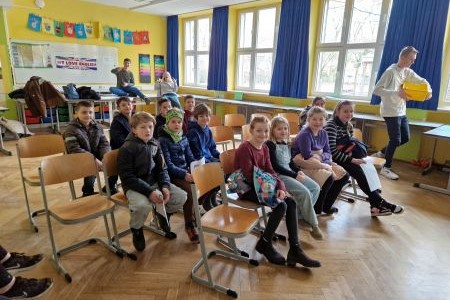 Mehrere Personen die in einem Klassenzimmer auf Stühlen sitzen