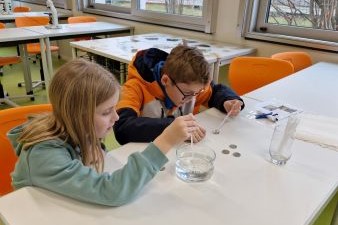 Personen die an einem Tisch sitzen mit Pipetten in der Hand